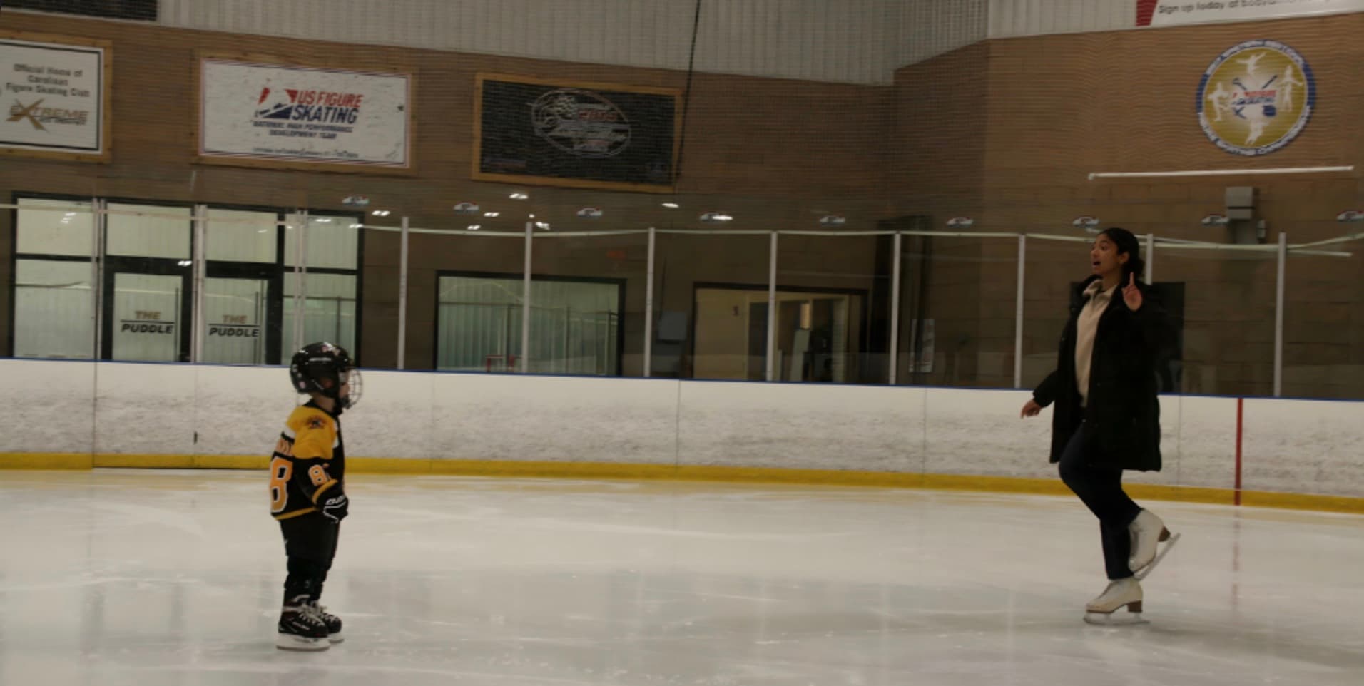 Coach Sami working with a young hockey player on the ice
